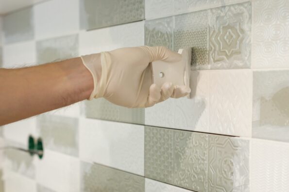 Closeup of tiler hand rubbing tile, Installing and grouting decorative finishes