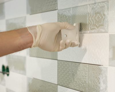 Closeup of tiler hand rubbing tile, Installing and grouting decorative finishes