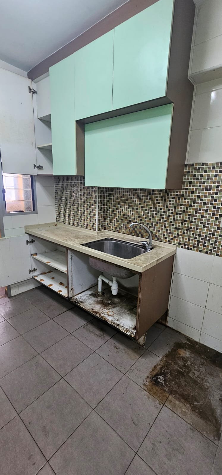 Before: Old HDB kitchen with worn mint-green cabinets, exposed sink pipes, and mosaic backsplash
