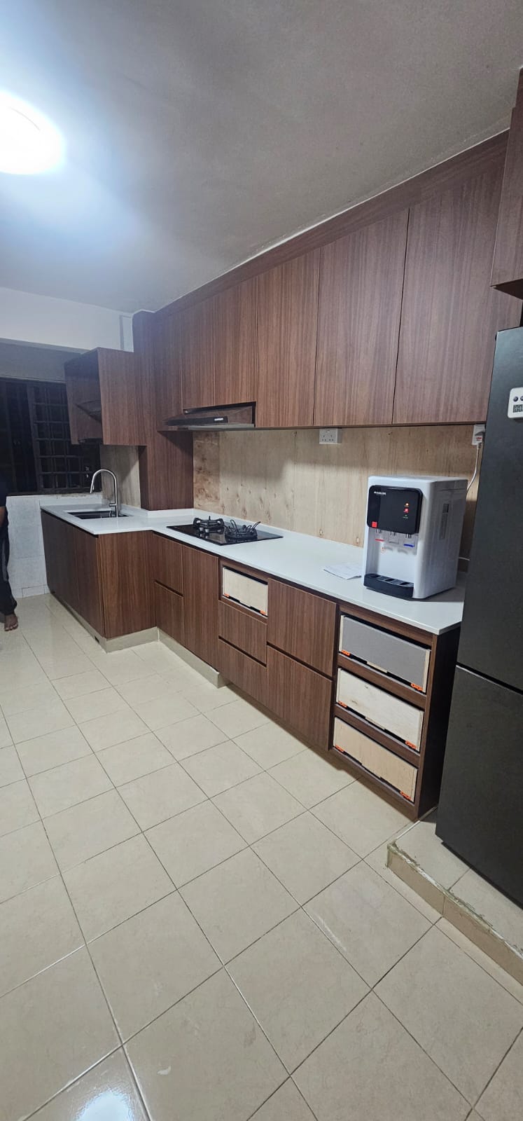 After: New walnut-laminate L-shaped kitchen cabinets with white countertop, hood, and gas hob
