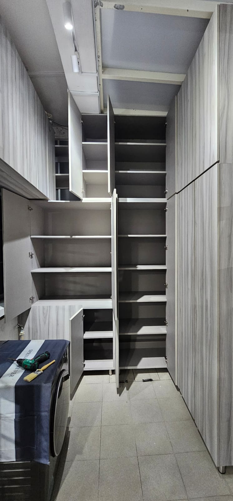 After: Custom floor-to-ceiling storage cabinets in light wood laminate