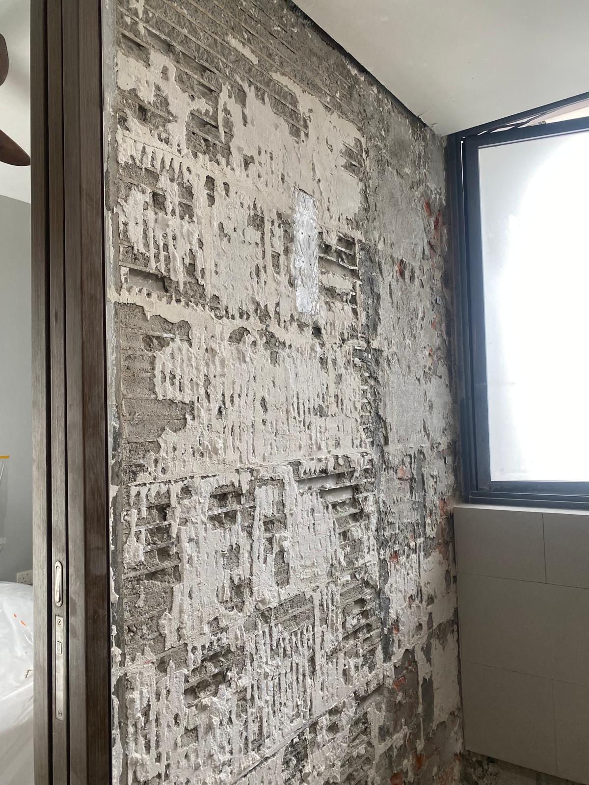 Before: Hacked bathroom wall with old tiles removed, bare concrete exposed