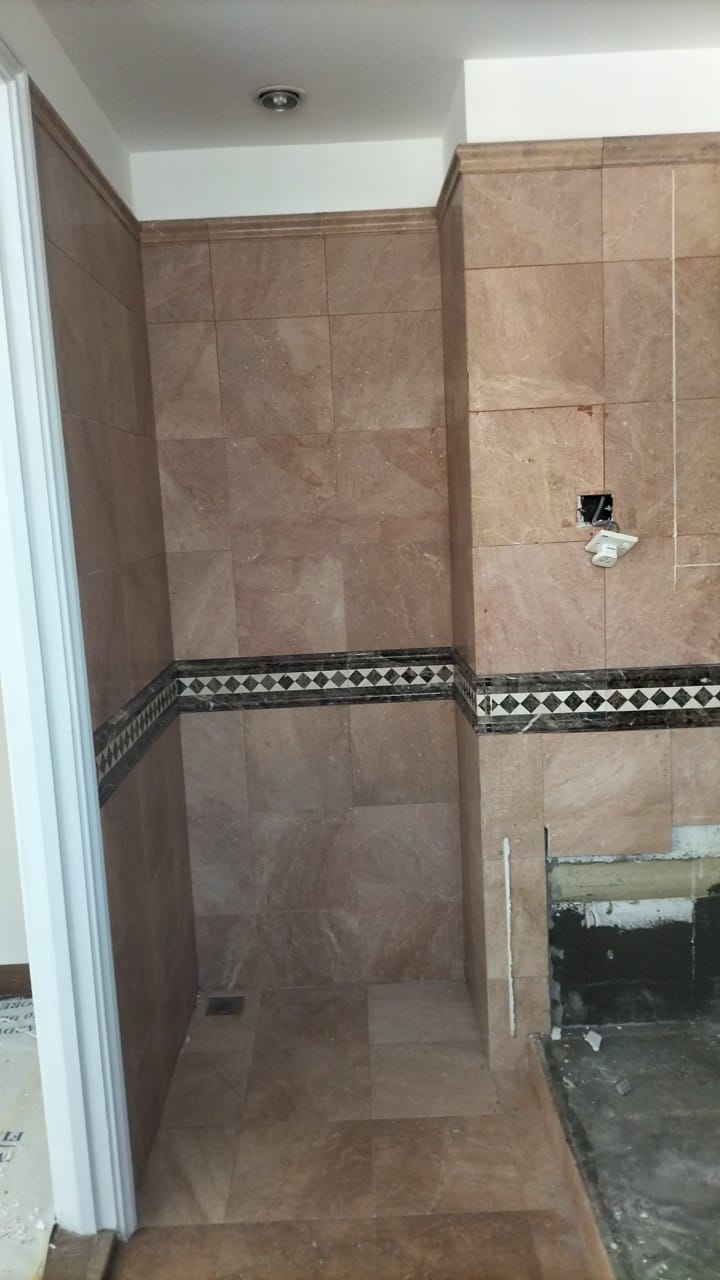Before: Condo bathroom with marble wall tiles and diamond border, vanity area under construction